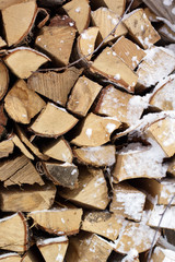 Chopped firewood logs in a pile with snow