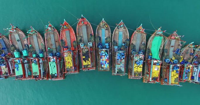Aerial view on fishing boats are parked in one line at the pier.