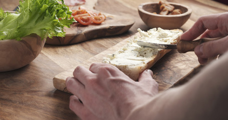 man spread cream cheese with herbs over baguette in slow motion, 4k photo