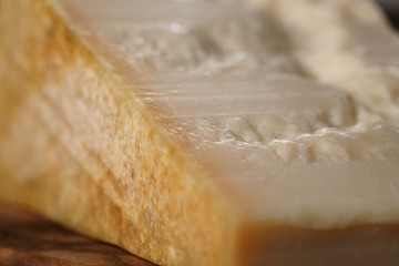 closeup of piece of italian parmesan cheese on wooden cutting board, simple rustic photo