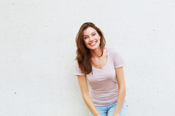 beautiful young lady standing against white wall and smiling