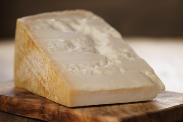 closeup of piece of italian parmesan cheese on wooden cutting board, simple rustic photo