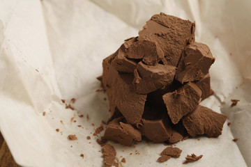chunks of gianduja hazelnut milk chocolate on paper, closeup photo