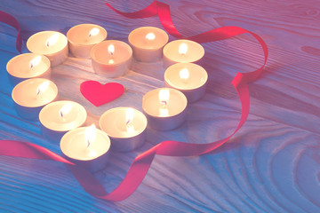 love symbol made from many small candles on wooden background