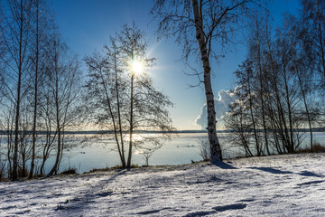 Wunderschöne Winterlandschaft bei strahlendem Sonnenschein und blauem Himmel an einem See