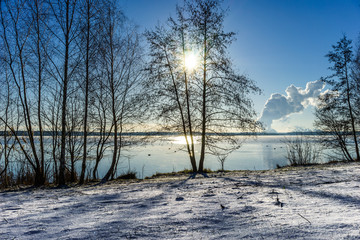 Wunderschöne Winterlandschaft bei strahlendem Sonnenschein und blauem Himmel an einem See
