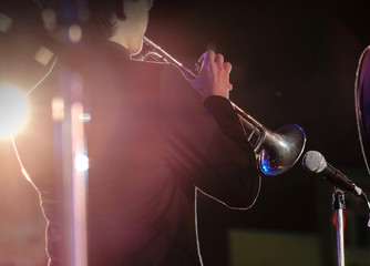 Jazz / View of bugler blowing the trumpet in concert at night. Movement. Shallow depth of field.
