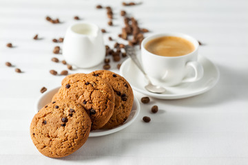 Oatmeal cookies, coffee grains and cup of hot coffee on white table