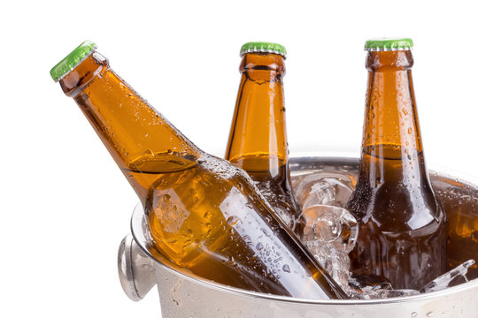 cold bottles of beer in bucket with ice on white background.