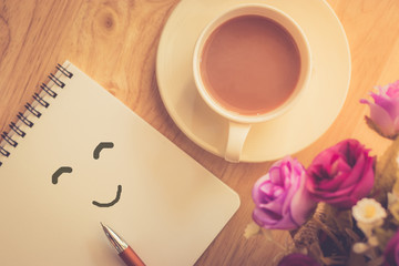 Happy weekend concept. White cup of coffee on wooden floor with .purple flower in pot  vintage color tone.