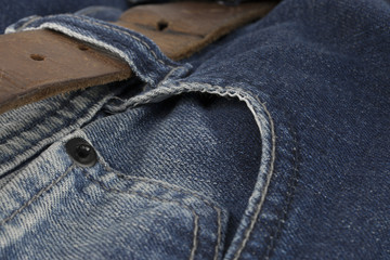 Detail of leather belt on a blue jeans.