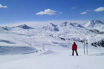 Fototapeta na wymiar Snowboarding and skiing on fresh snow slopes in an alpine valley, Paradiski, Plagne, Alps, France
