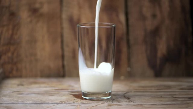 Domestic milk in glass over wooden background. Closeup. 