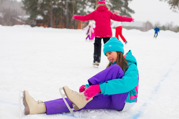 young attractive skater girl sitting on the ice