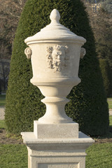 decorative vase with the head of a satyr in a classical park