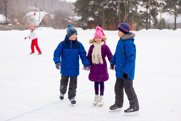 two boys helps girl learn to skate