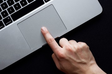 Hand using trackpad on laptop over black background - 132445825