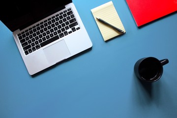 Laptop, notebooks and mug on bright blue desk - 132445832