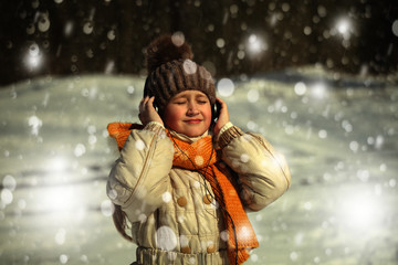 Девочка слушает музыку в наушниках, в зимний день идет снег.