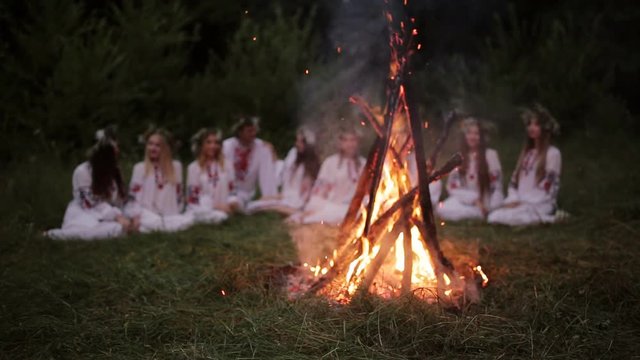 Midsummer. Young people in Slavic clothes sitting in the woods near the fire.