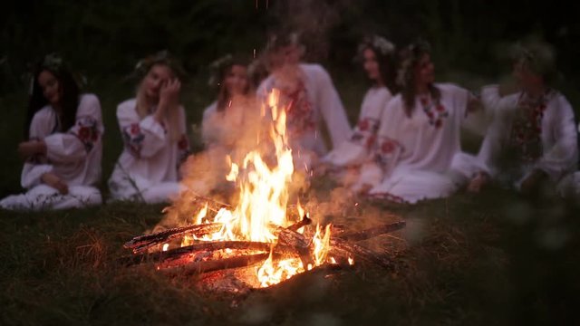 Midsummer night. Young people in Slavic clothes sitting near the bonfire.