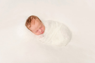 funny swaddled in white costume baby sleeping on blanket