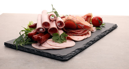 Food tray with delicious salami, pieces of sliced ham, sausage, tomatoes, salad and vegetable - Meat platter with selection