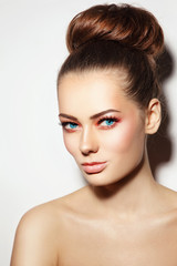 Fototapeta premium Young beautiful healthy woman with stylish make-up and hair bun over white background, copy space