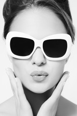 Black and white portrait of young beautiful woman in vintage sunglasses