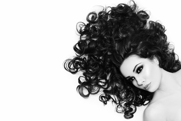 Black and white shot of young beautiful sexy woman with dark long curly hair, copy space