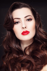 Portrait of young beautiful woman with long curly hair and red lipstick