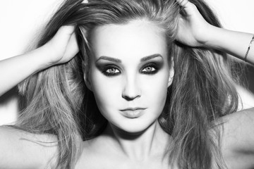 Naklejka premium Black and white portrait of young beautiful woman with smoky eyes touching her hair