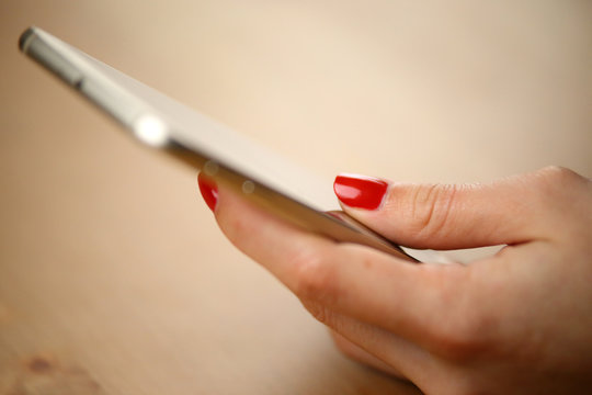 Smartphone tactile avec main d'une jeune femme vernis rouge sexy sur son téléphone portable