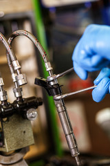 Professional mechanic testing diesel injector in his workshop.