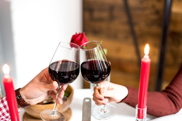 Young happy couple celebrating Valentine's day with a dinner at home drinking wine, cheers.