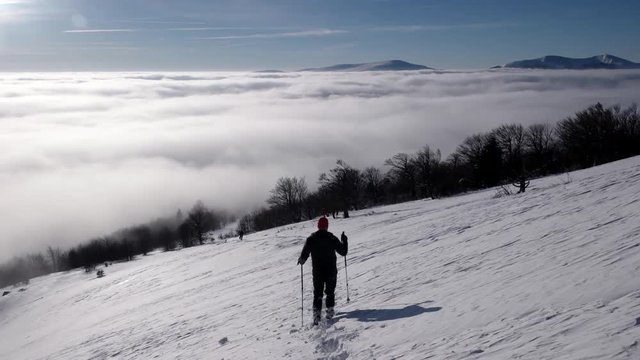 Travellers With Backpacks Make a Winter Hike Above the Clouds With a View of the Distant Peaks by a Coast of the Cloud Sea
