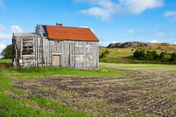 Old and abandoned wooden house with red roof in the Norwegian countryside