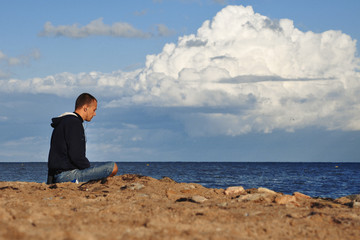 Fototapeta na wymiar man sitting on the beach and medetiruet