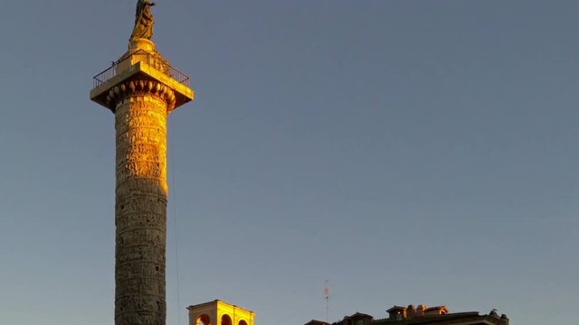 Zoom on the column of Marcus Aurelius at sunset in Piazza Colonna Rome, Italy.