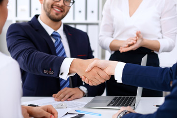 Business handshake at meeting or negotiation in the office. Partners are satisfied because signing contract or financial papers