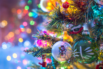 Part of Christmas tree, with colorful glass balls, small decorations and colorful light reflections