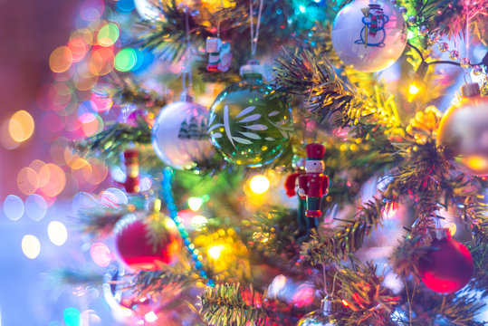 Part of Christmas tree, with colorful glass balls, small decorations and colorful light reflections