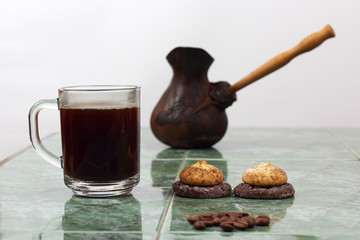 cup of black coffee on a plate next to the vessel for brewing co