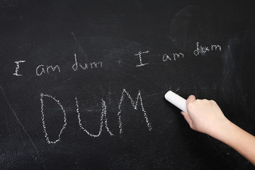 I am dumb, spelled wrong written on a blackboard