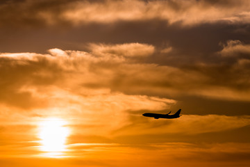 Fototapeta na wymiar A plane flying towards a beautiful sunset