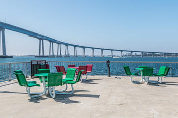 Dining area on the viewing pier at Cesar Chavez Park in San Diego, California, with Coronado bridge in the background.