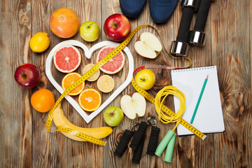 Diet, centimeter and dumbbells on a wooden background