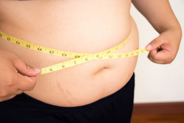 Woman body fat with measure tape.