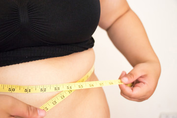 Woman body fat with measure tape.