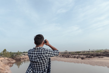 Tourist man looking through binoculars on the coast.